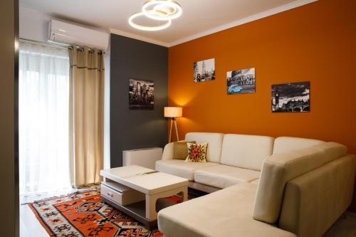 sala de estar con paredes de color naranja y sofá en Vasho Luxury Apartment, en Gjirokastra