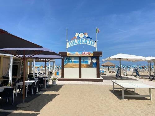 ein Schild am Strand mit Tischen und Sonnenschirmen in der Unterkunft Hotel Blue Ribbon in Rimini