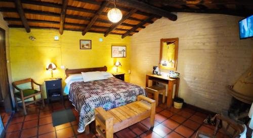a bedroom with a bed and two tables and a chair at Villa Patzcuaro Garden Hotel in Pátzcuaro