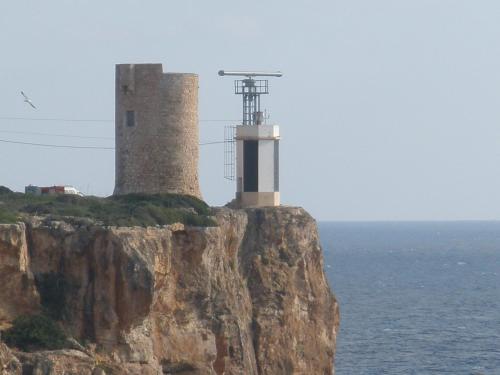 a lighthouse on top of a cliff next to the ocean at Hostal Can Jordi in Cala Figuera