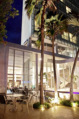 a building with tables and chairs and palm trees at Estelar Apartamentos Barranquilla in Barranquilla