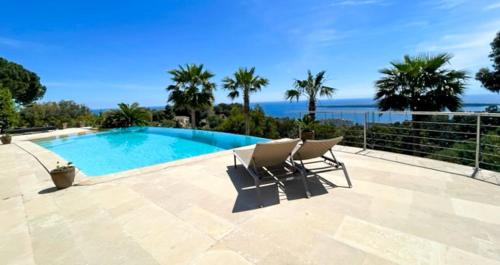 une piscine avec deux chaises et l'océan dans l'établissement Clos des Iles, Havre de paix vue mer à 10 minutes du Palais, à Vallauris