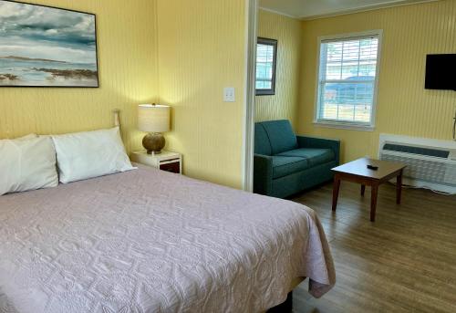 a bedroom with a bed and a couch and a chair at Seashell Village Resort near the beach with kitchens in Port Aransas