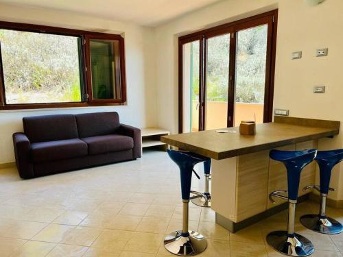 a living room with a couch and a table and stools at Villetta con vista mare e parcheggio in Isola del Giglio