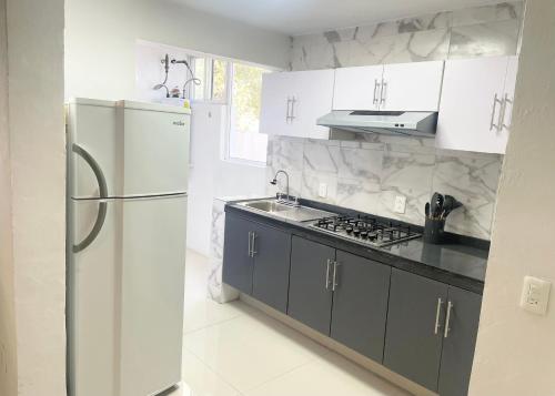eine weiße Küche mit einem Kühlschrank und einer Spüle in der Unterkunft Suite Jacarandas 103 in Guadalajara