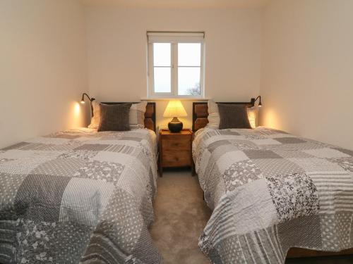 two twin beds in a room with a window at Reubens Cottage in Barnstaple