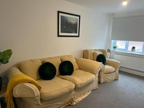 a living room with a couch with two pillows on it at Village House Cardiff - Close to A48 and M4 in Cardiff