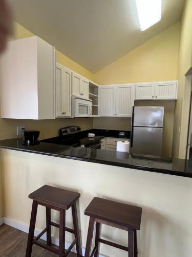 a kitchen with white cabinets and two bar stools at Seashell Village Resort near the beach with kitchens in Port Aransas