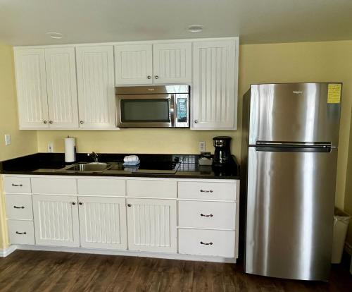 a kitchen with a stainless steel refrigerator and white cabinets at Seashell Village Resort near the beach with kitchens in Port Aransas