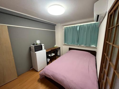 a small bedroom with a pink bed and a window at 玉藻藤塚町 in Takamatsu