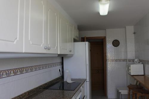 uma cozinha com armários brancos e um frigorífico branco em Mar Azul Solo Familias Serviplaya em Casas Las Basas