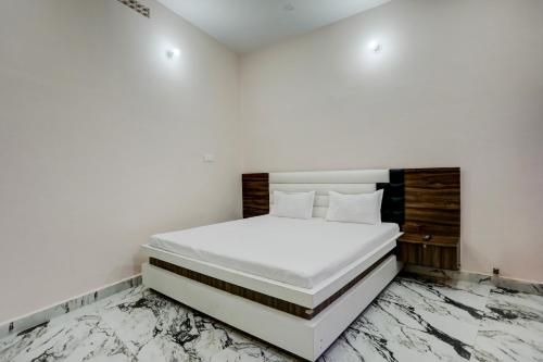 um quarto branco com uma cama branca e pisos em mármore em Super OYO Shivansh banquet and hotel em Dhanbad