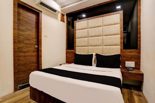 a bedroom with a large bed with a wooden headboard at OYO Flagship Hotel Ashirwad Inn in Mumbai
