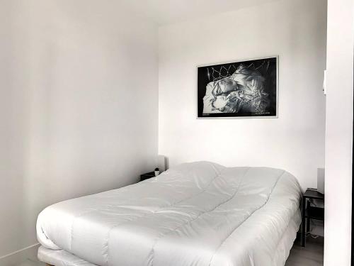 a white bed in a room with a picture on the wall at 106 - Appartement rénové Sables d'Or Les Pins in Fréhel