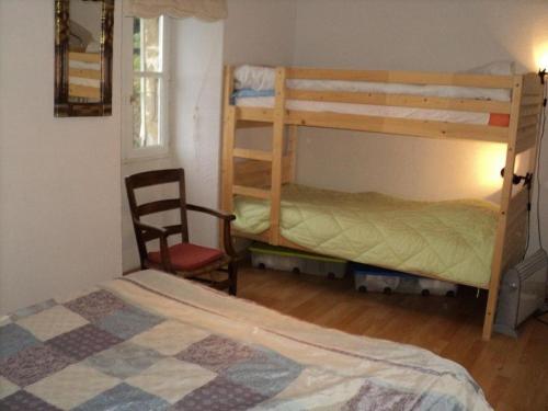 1 dormitorio con 2 literas y 1 silla en Maison En Pierres Proche Agnac en Firmi