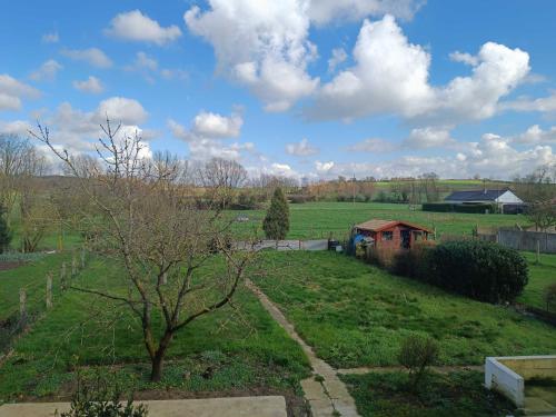 a view of a field with a house and a tree at Le Perchoir in Saint-Jans-Cappel