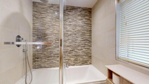 a bathroom with a shower and a bath tub at Cherry Tree Cottage in Bicester