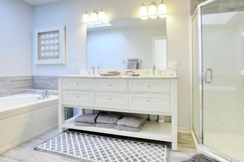 a bathroom with a sink and a tub and a mirror at Cheerful 3 Bedroom Beach Front Cottage with Fire Place in Milford