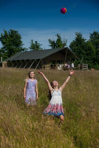 two girls playing with a red frisbee in a field at Cuckoo Down Farm Glamping in Venn Ottery