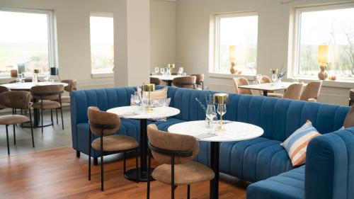 a restaurant with a blue couch and tables and chairs at HotelVFjorden in Lemvig