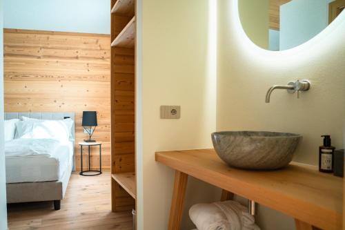 a bathroom with a sink and a bed and a mirror at Vivi Suites & Spa - Boutique Guest House Molveno in Molveno