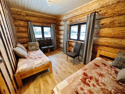 a bedroom with a bed and chairs in a log cabin at Alliku holiday home in Alliku
