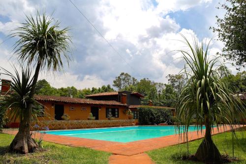 a house with a swimming pool and two palm trees at Villa Patzcuaro Garden Hotel in Pátzcuaro