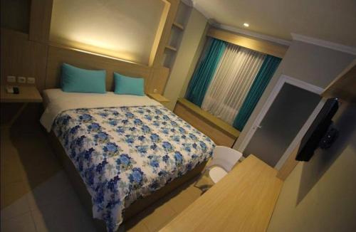 a bedroom with a bed with blue pillows and a window at D’Coz Surya Living Pakuwon in Surabaya