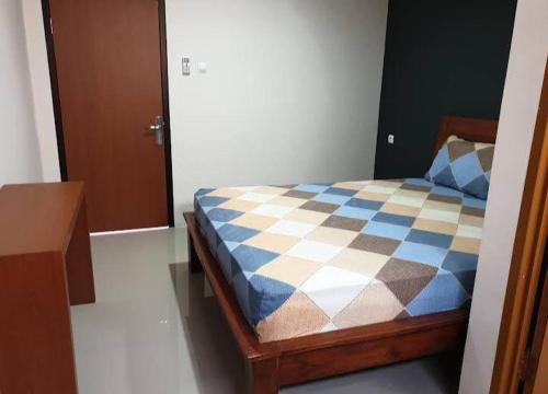 a bedroom with a bed with a blue and white checkered bedspread at D’Coz Surya Living Pakuwon in Surabaya