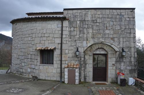 un edificio in pietra con una porta e un gatto seduti all'esterno di Casale di Pesche a Pesche
