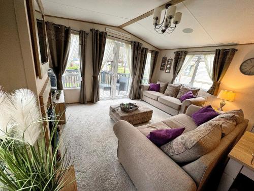 ein Wohnzimmer mit Sofas und lila Kissen in der Unterkunft Hopton Lodge Retreat in Great Yarmouth