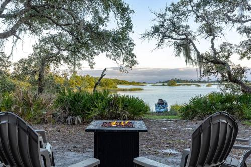 two chairs and a table next to a lake at 3 Story Haven Fire Pit kayaks updated 360 Views in Cedar Key