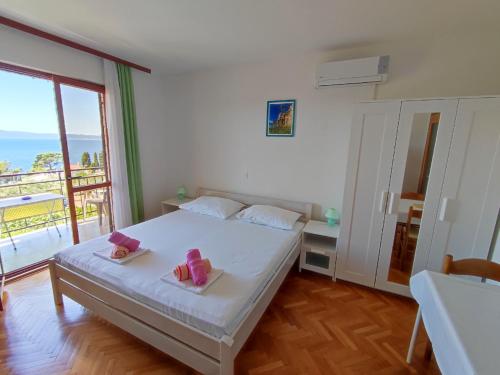 a bedroom with a white bed and a balcony at Apartments Slaven in Podgora