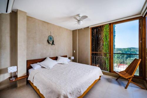 ein Schlafzimmer mit einem Bett und einem großen Fenster in der Unterkunft Spacious & Serene With Partial Ocean & Jungle View in Tamarindo