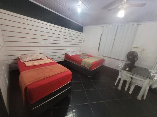 2 Betten in einem Zimmer mit einem Schreibtisch und einem Tisch in der Unterkunft Hospedaria cmc unidade 03 Com Estacionamento in Riacho Fundo