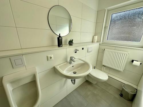 a bathroom with a sink and a toilet and a mirror at renovierte & voll möblierte Wohnung für 7 Personen in Minden