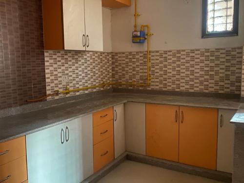 uma cozinha vazia com armários laranja e branco em My Space em Agra