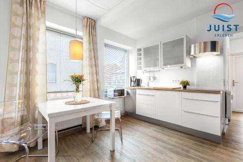 a kitchen with white cabinets and a table with flowers on it at Landhaus Gertrude 105 - Wohnung Wattenmeer in Juist