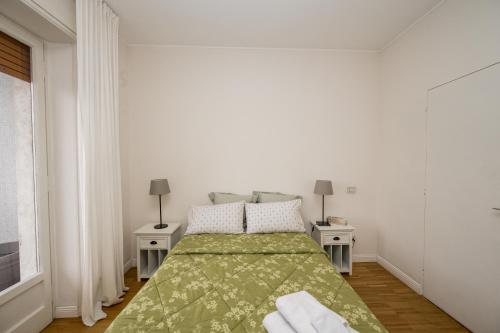 1 dormitorio blanco con 1 cama verde y 2 mesas en Home Sweet Home, en Milán