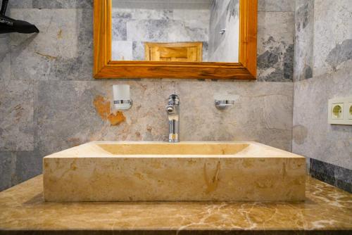 a bathroom with a stone sink with a mirror at Cave Hotel Saksagan in Göreme