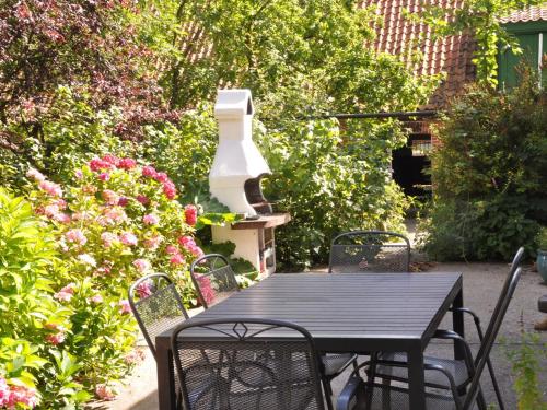 a black table and chairs in a garden with flowers at Ferienwohnung im Gutshaus I Gut Kirchmühl I Ostsee in Kirchnüchel