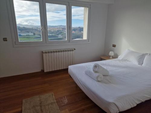 1 dormitorio con 1 cama blanca y 2 ventanas en Pensión Aussie II, en San Sebastián