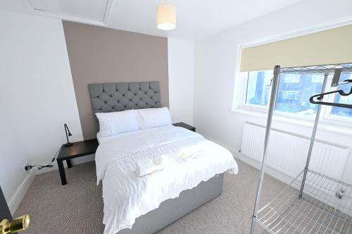 a white bedroom with a bed and a window at Vibrant 3BD home with great links to the city in London