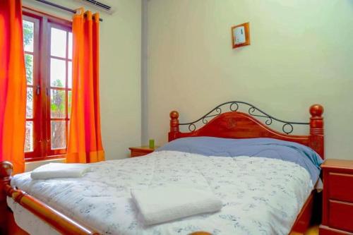 een slaapkamer met een groot bed en oranje gordijnen bij Deer Point Hotel Kandy in Kandy