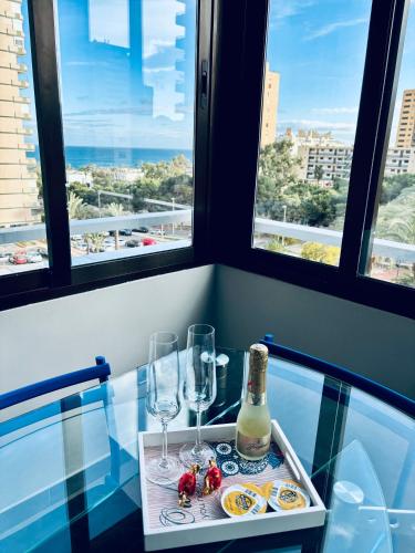 una mesa de cristal con dos copas y una botella de vino en Apartamento en Aguadulce Playa con vistas al mar y piscina, en Aguadulce