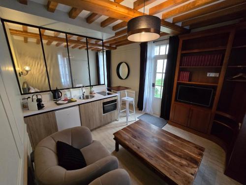 Au Loup Historic Apartments في بايو: غرفة معيشة مع مطبخ مع طاولة وأريكة