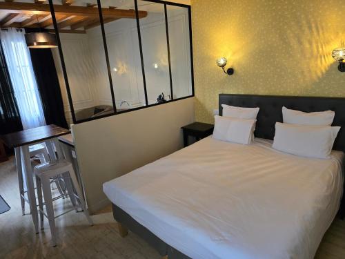 a bedroom with a large bed with white sheets at Au Loup Historic Apartments in Bayeux