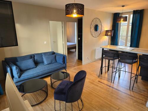 a living room with a blue couch and a table at Au Loup Historic Apartments in Bayeux