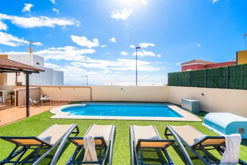 a patio with chairs and a swimming pool on a roof at Villa Trueno Refugio de Lujo con Piscina Climatizada y Vistas in Candelaria