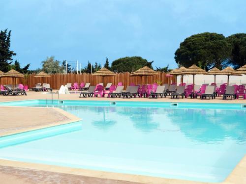 une grande piscine avec des chaises et des tables roses dans l'établissement Camping Saint-Nazaire, à Saint-Nazaire